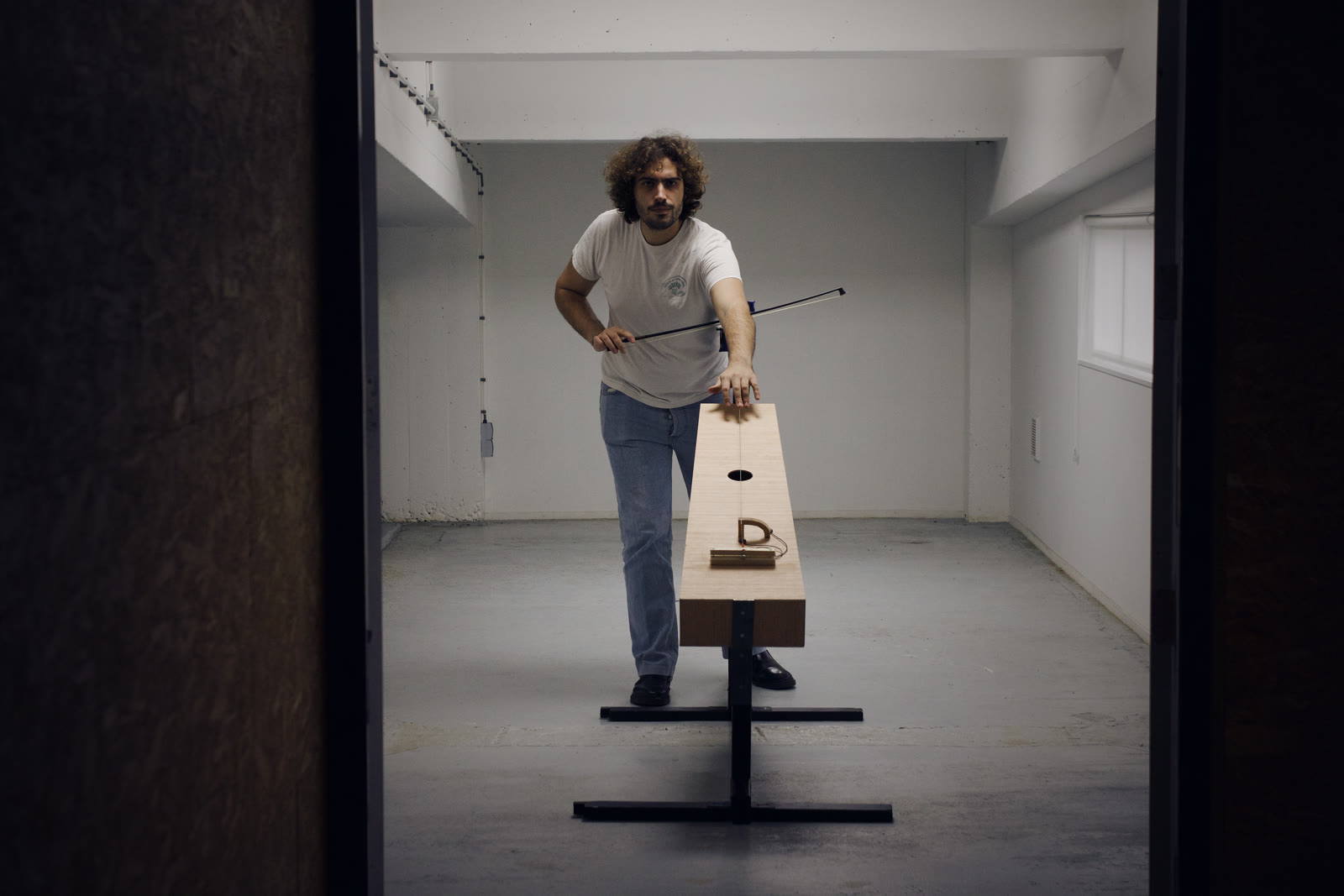 Lorenzo Servali playing the trombone marino, seen through a doorway